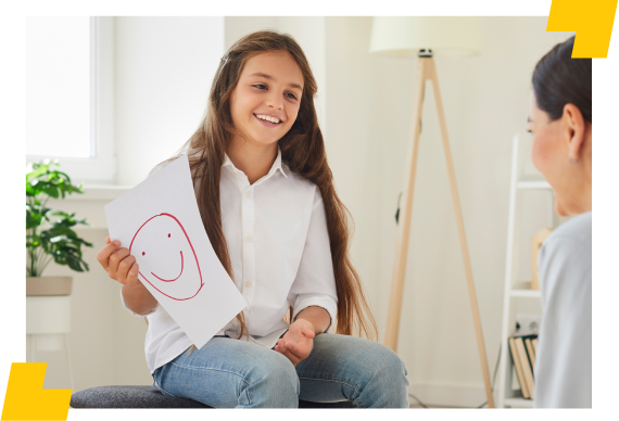 Menina sorridente segurando desenho de rosto feliz